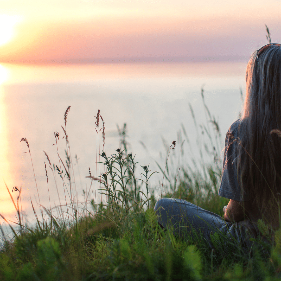 Image of lady relaxing in nature and looking at the sunset