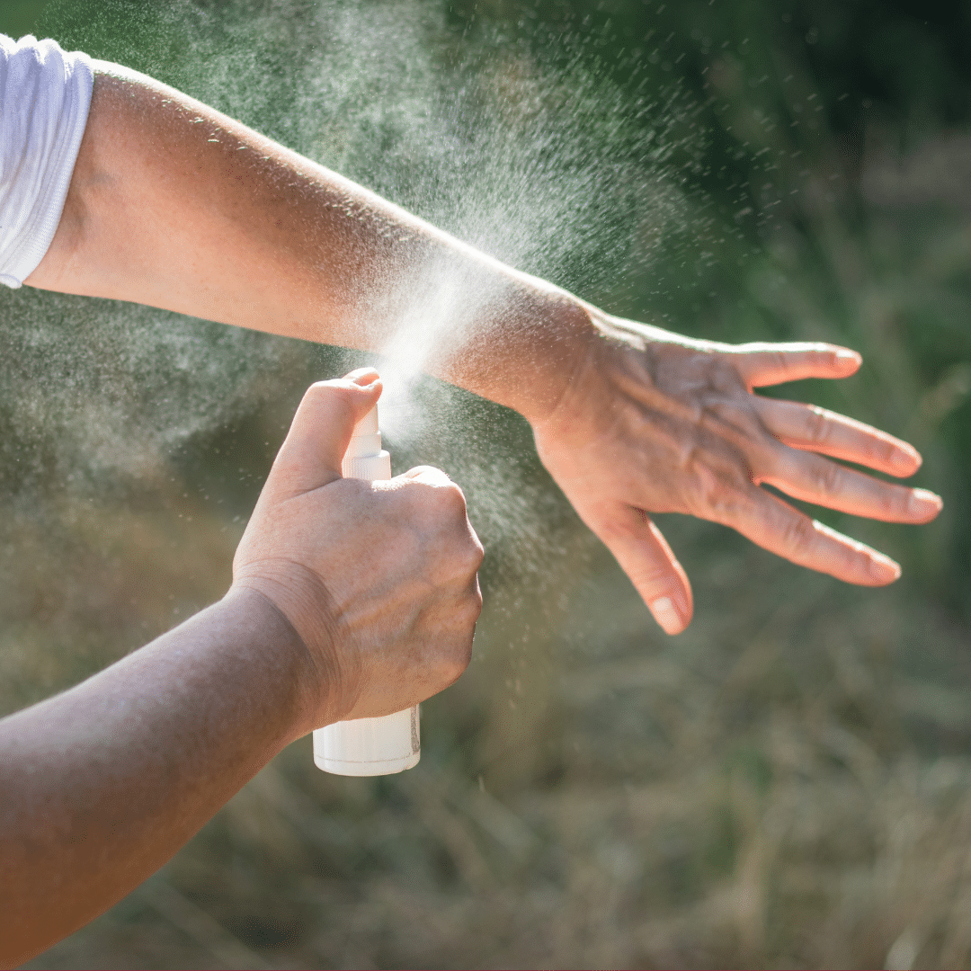 Image of someone spraying insect repellent